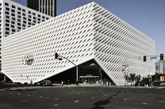 a large white building sitting on the side of a road next to tall skyscrapers