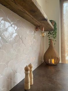 two vases sitting on top of a counter next to a wooden shelf and window