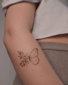 a woman's arm with a butterfly and flowers tattoo on the left side of her arm