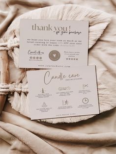 two thank you cards sitting on top of a bed next to a pillow and blanket