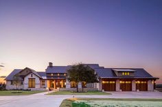 a large house with two car garages in front of it at sunset or dawn