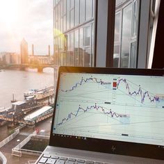 an open laptop computer sitting on top of a window sill next to a river