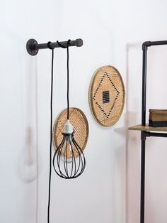 two woven baskets hanging on the wall next to a shelf with books and a lamp