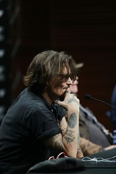 a man with long hair sitting in front of a microphone