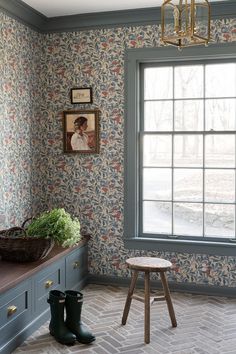 a room that has a window and some flowers on the wall in front of it