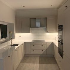 an empty kitchen with white cabinets and wood flooring