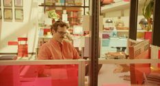 a man sitting at a desk in front of a window with pink sticky notes on it