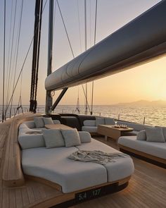 the sun is setting over the ocean on a sailboat with chaise lounges