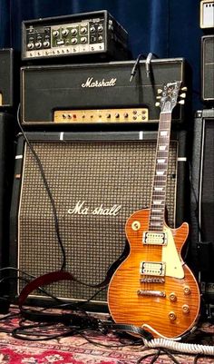 an electric guitar sitting on top of a carpet next to two amps and speakers