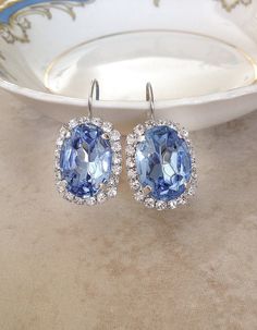 Gorgeous pair of statement size earrings featuring 18x13mm light Sapphire blue oval rhinestones surrounded by tiny sparkling clear crystals. Lever back closure for pierced ears. Thanks for stopping by. Blue Bling Wedding Jewelry, Blue Bling Jewelry For Wedding, Blue Halo Setting Earrings For Wedding, Blue Oval Party Jewelry, Blue Halo Earrings For Wedding, Blue Oval Earrings For Wedding, Bridal Party Blue, Wedding Something Blue, Sapphire Blue Earrings