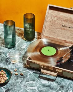 an old record player sitting on top of a table next to some glasses and nuts