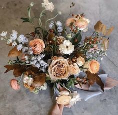 a bouquet of flowers is being held up by someone's hand on the floor