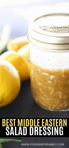 a jar filled with salad dressing next to lemons