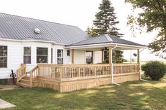 a white house with a metal roof and wooden steps leading up to the front porch