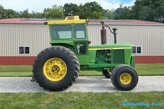 a green tractor parked in front of a building