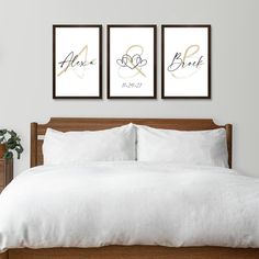 a bed with white sheets and two pictures on the wall above it that say love