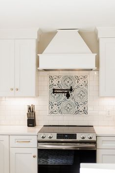 a stove top oven sitting inside of a kitchen next to white cabinets and counter tops