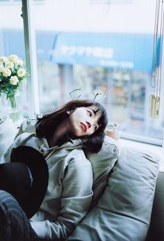 a woman laying on top of a couch next to a window