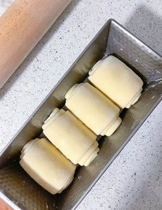 four uncooked dough rolls in a metal pan