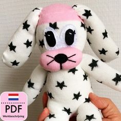 a hand holding a white and black stuffed animal with stars on it's face