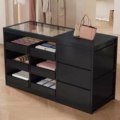 a black dresser with drawers and purses on it