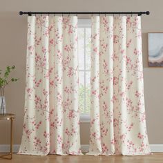 a living room with white curtains and pink flowers on the window curtain rod, in front of