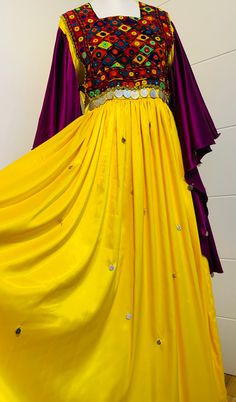 This completely unique traditional vintage-style Afghan dress blends modern styling (with an elegant long satin skirt and flowing sleeves) with traditional Afghan tribal 'kuchi'(nomad) colours, paisa coins, and embroidery on the chest area which took over a month to make by hand. Suitable for all occasions including weddings and parties.  The dress is most suited to a 'Medium' build but one size fits many as it can be tied from the back to adjust accordingly. Dimensions: Chest (armpit to armpit) Traditional Long Purple Dress, Traditional Yellow Dress For Festivals, Yellow Bohemian Dress For Festivals, Festive Yellow Festival Dress, Festival Kaftan With Dabka Detailing, Silk Festival Dress With Dupatta, Yellow Bohemian Dress For Festive Occasions, Yellow Dresses For Eid And Traditional Ceremonies, Gold Bohemian Dress With Traditional Drape