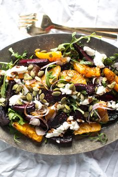 a salad with beets, oranges and feta cheese in a metal bowl