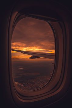 an airplane window looking out at the sunset