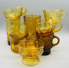 an assortment of yellow glass cups and saucers