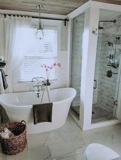 a white bath tub sitting under a window next to a toilet and shower stall in a bathroom