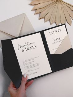 a person holding an open black and white wedding card