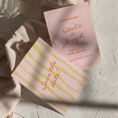 two pink and yellow wedding cards sitting next to each other on top of a table