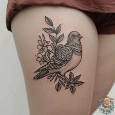 a woman's thigh with a bird and flowers tattoo on the side of her leg