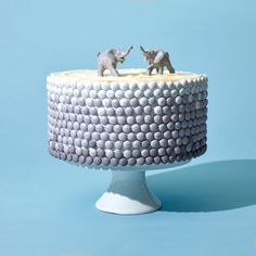 two small elephants on top of a cake with white frosting and grey icing