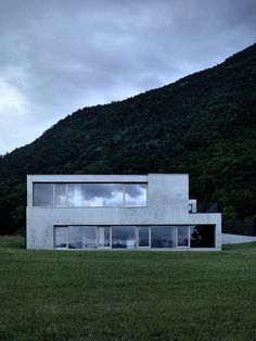 a large white building sitting on top of a lush green field next to a mountain