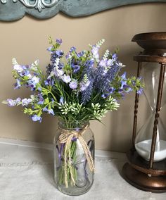 a vase filled with purple flowers sitting on top of a table next to an hour clock