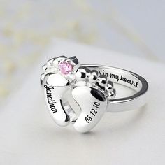 two heart shaped silver rings with pink crystal stones in the middle and personalized names on them