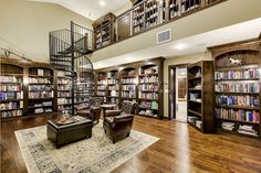 a living room filled with lots of furniture and bookshelves next to a spiral staircase