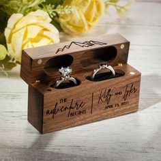 two wedding rings are in a wooden box