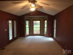 an empty living room with red walls and ceiling fan