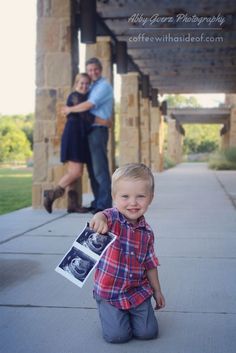 a young boy holding an old photo in front of him and his parents on the porch