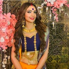 a woman in a blue and yellow outfit posing for the camera with flowers behind her