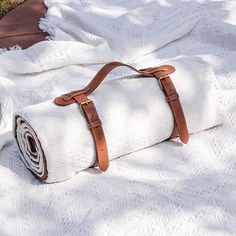 a white blanket with leather straps laying on the ground next to a roll of toilet paper