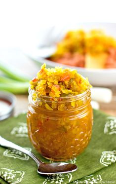 a jar filled with food sitting on top of a green napkin next to a spoon