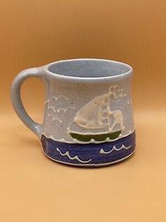 a white and blue mug with a boat on it