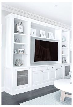 a living room with white bookcases and a flat screen tv on the wall