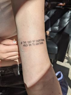 a woman with a tattoo on her arm that says at the end of everything, hold on to anything