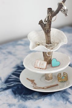 three tiered trays with jewelry on them and a tree branch sticking out of the top