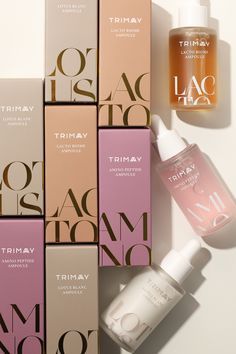 the bottles are next to each other on the white surface with pink and brown boxes